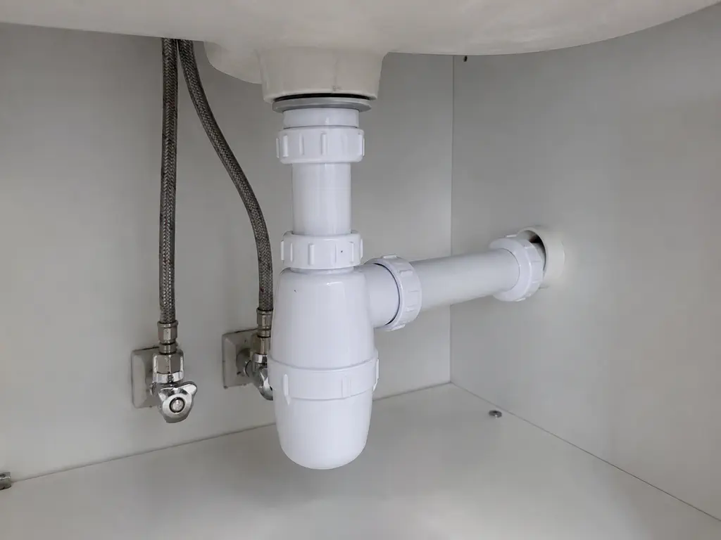 Siphon et raccords d’évacuation remplacés sous un meuble